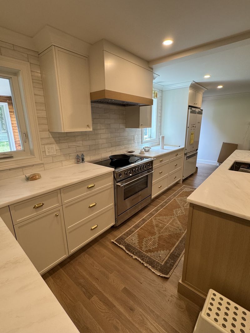 Custom cream kitchen cabinets with wood range hood and brass hardware