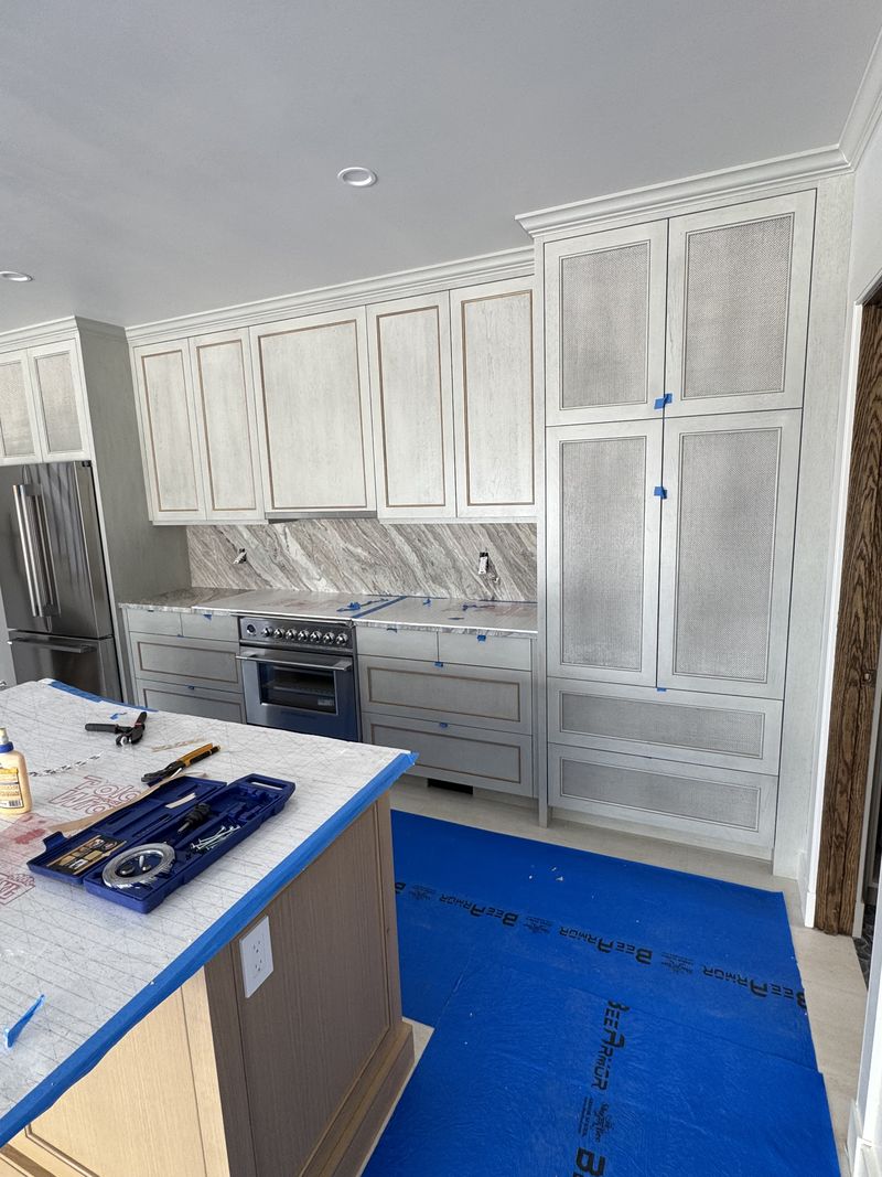 Custom kitchen cabinets and glass-front pantry during installation