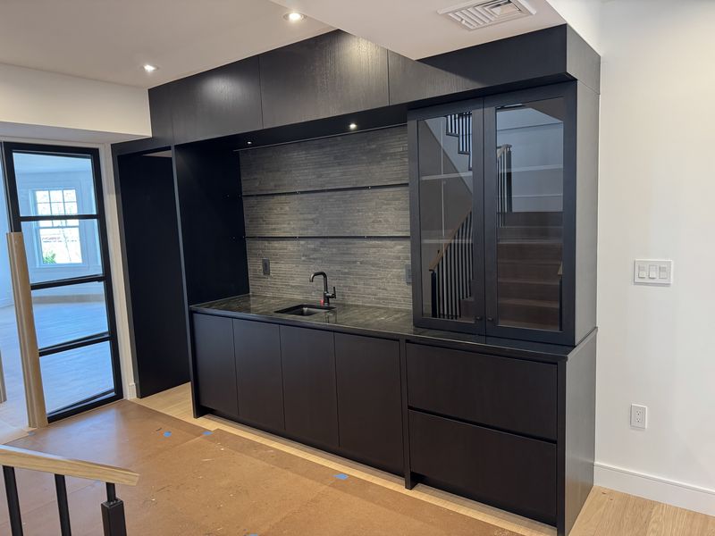 Custom black wet bar cabinetry with glass-front display cabinets