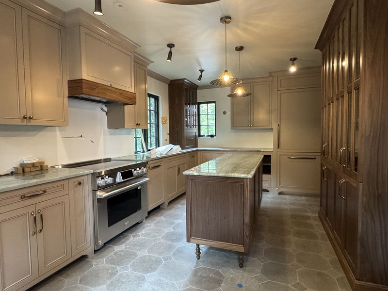 Custom taupe kitchen cabinets with wood hood and walnut island