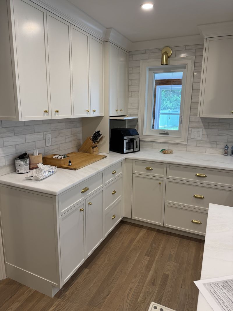 Custom white kitchen cabinets with brass pulls and tile backsplash