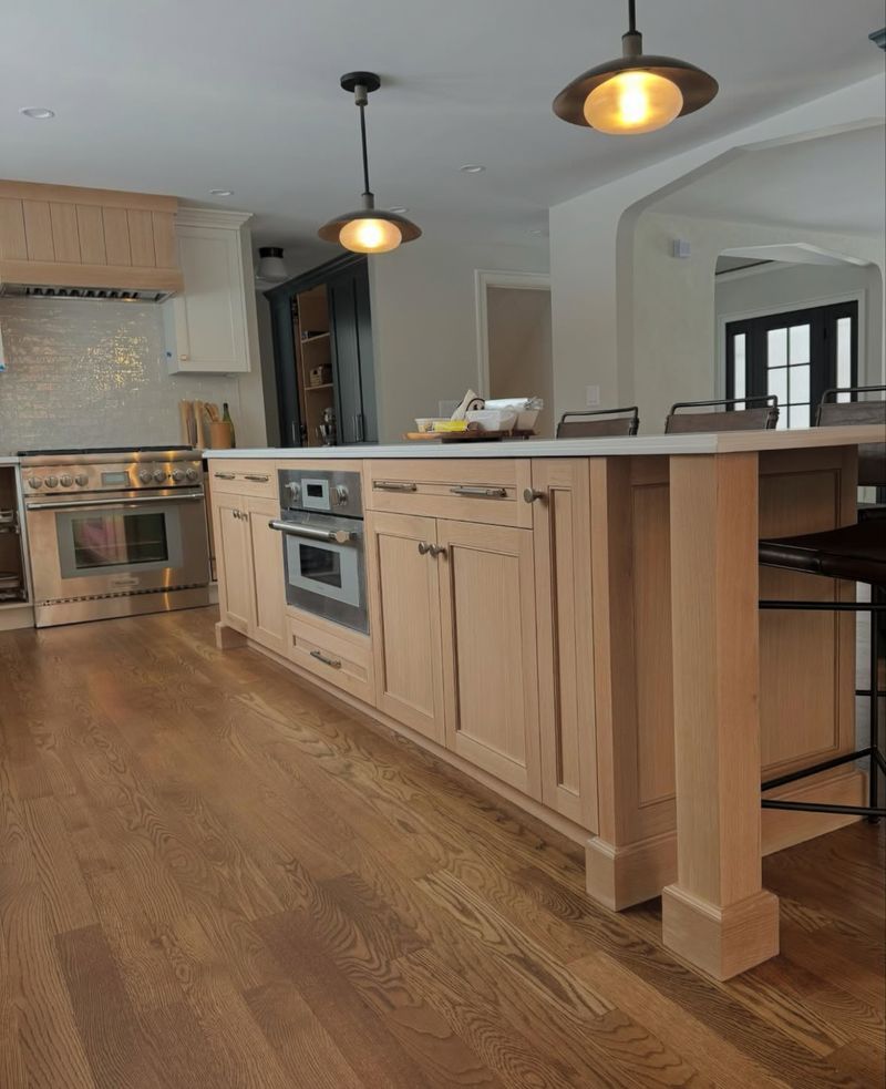 Custom white oak kitchen island with seating and integrated appliances